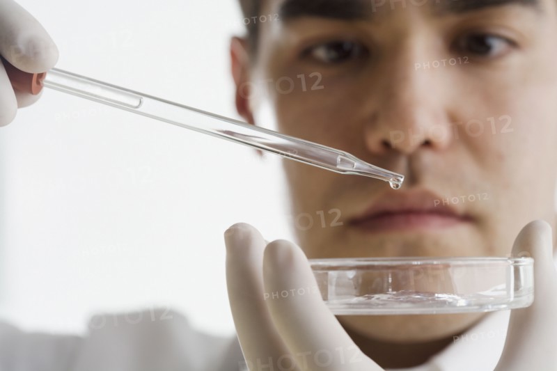 Scientist dropping chemicals into a Petri dish