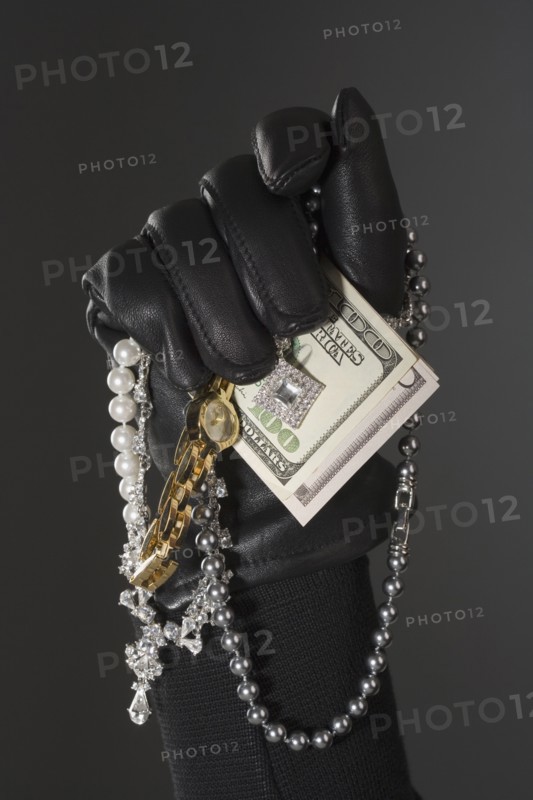Close up of gloved hand with money and jewels