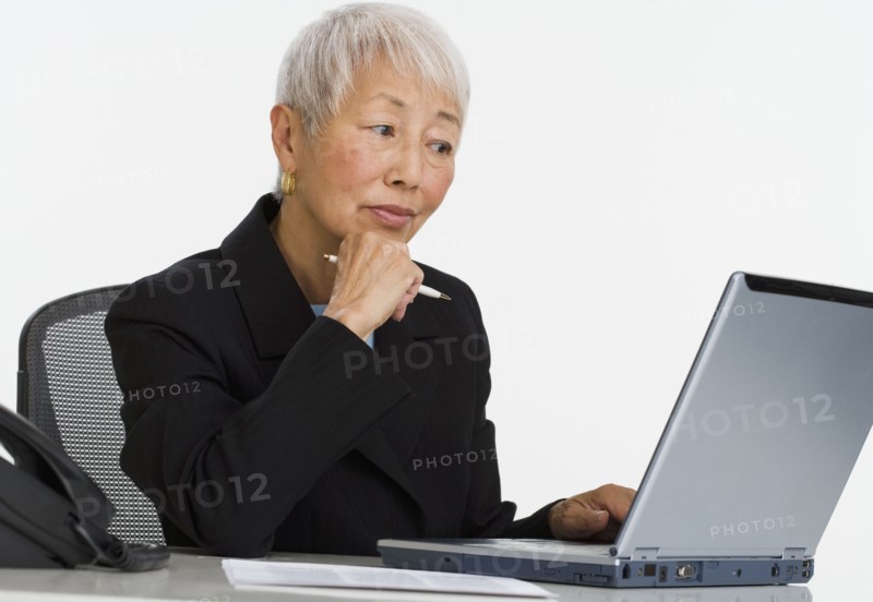 Senior Asian businesswoman using laptop at desk