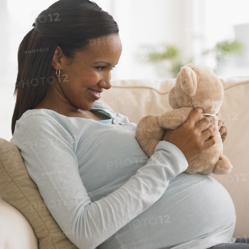 Pregnant African woman hugging teddy bear