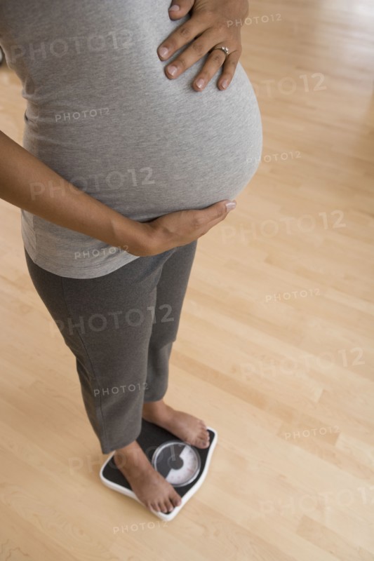 Pregnant African woman standing on scale
