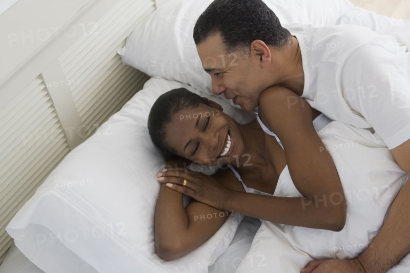 Middle-aged African couple hugging in bed