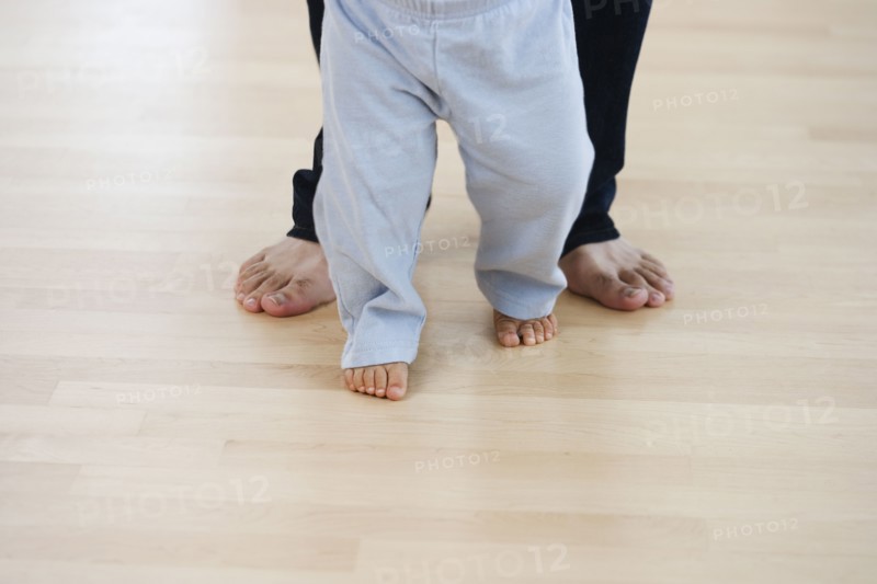 Low section of barefoot baby and father