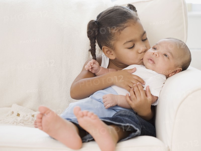 African girl kissing baby sibling