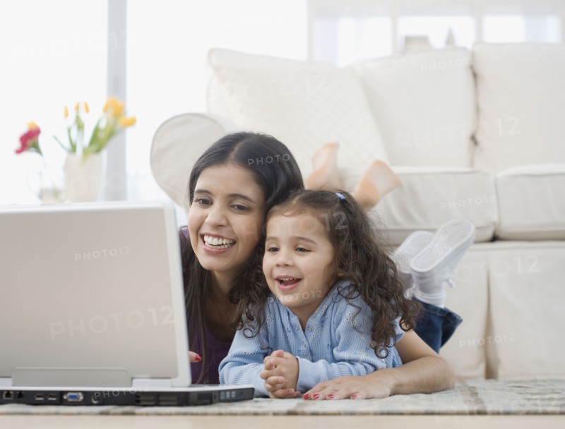 Hispanic mother and daughter looking at laptop