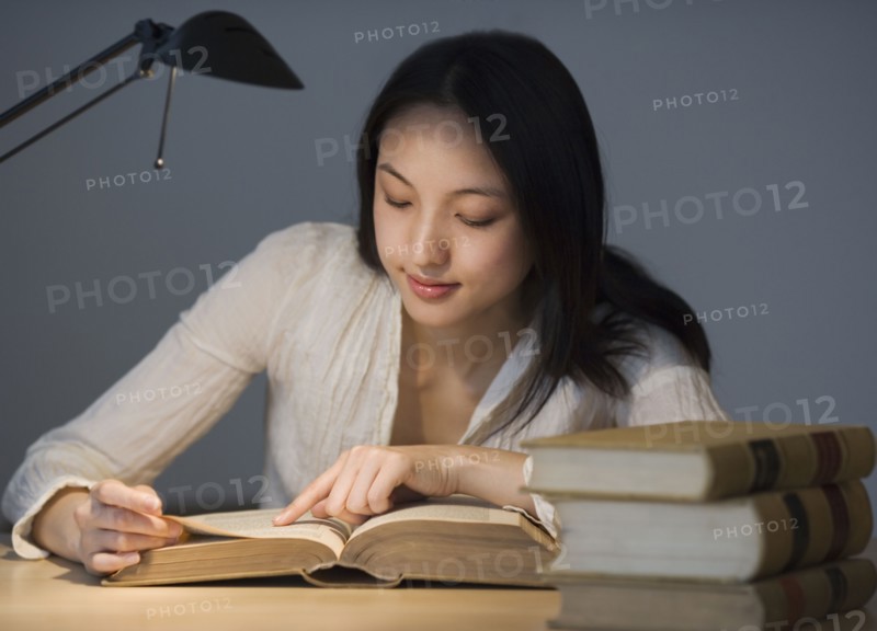 Asian woman reading at desk