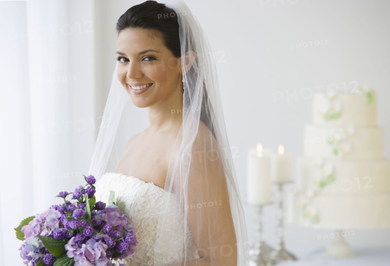 Hispanic bride holding bouquet of flowers