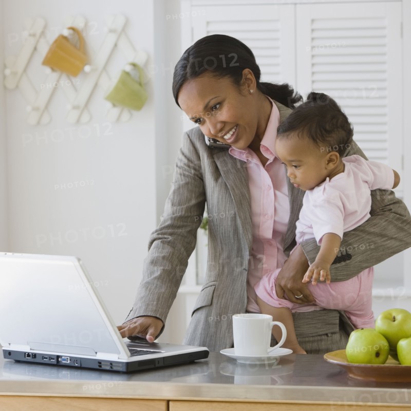 African American mother working at holding baby