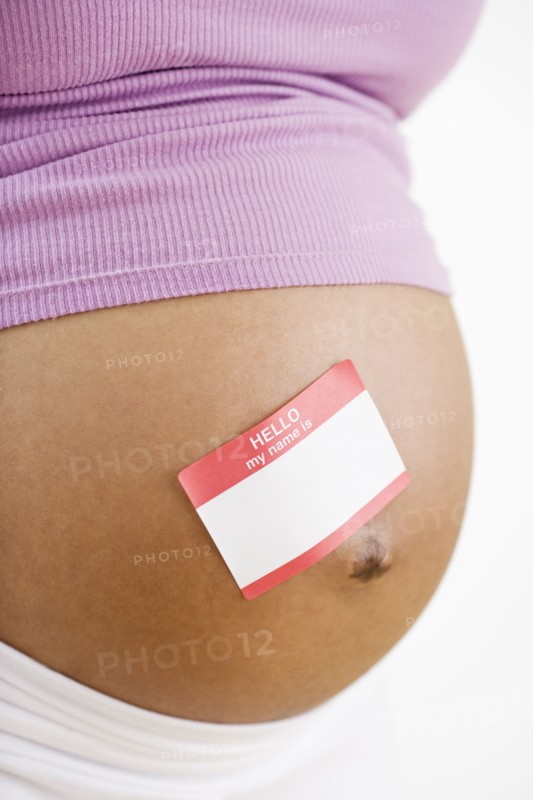 Pregnant African American woman with name tag sticker on belly