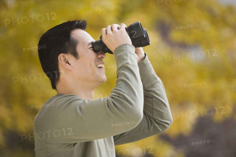 Asian man looking through binoculars