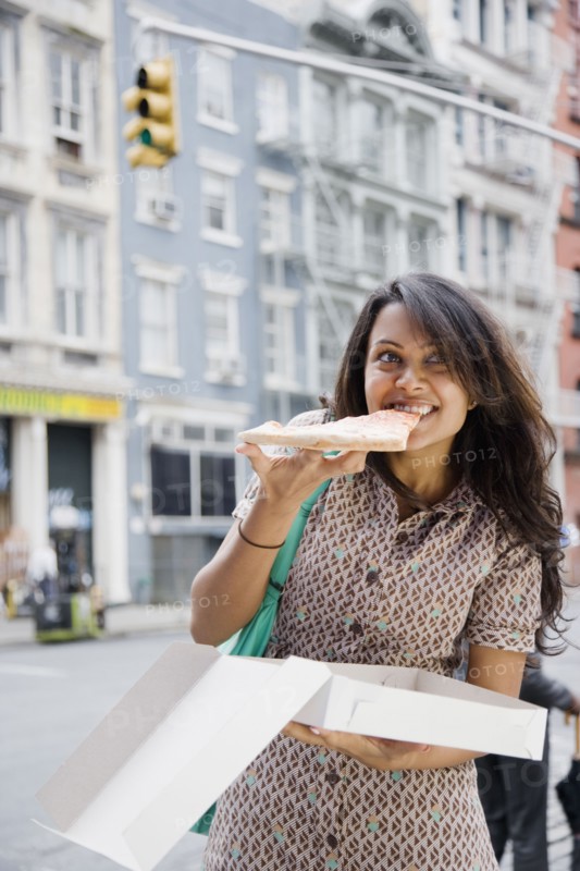 Mixed Race woman eating pizza