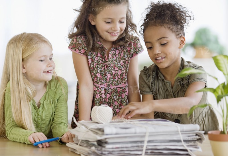 Multi-ethnic girls bundling newspapers