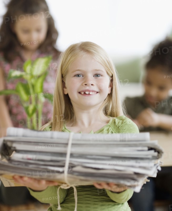 Girl holding bundle of newspapers