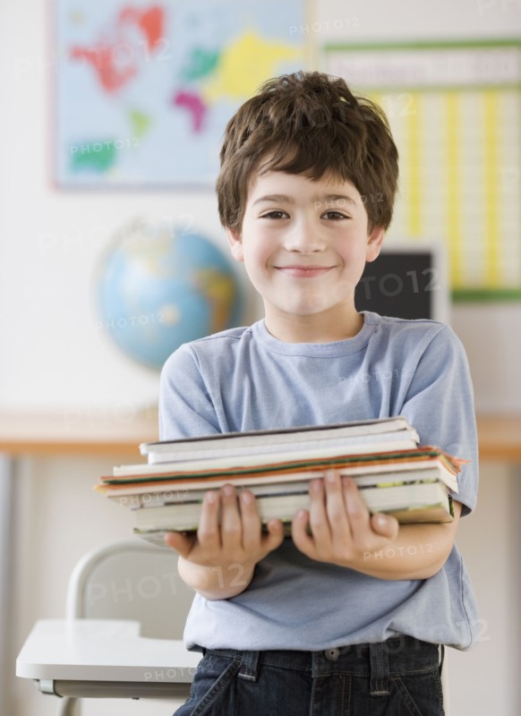 Hispanic boy holding stack of school books