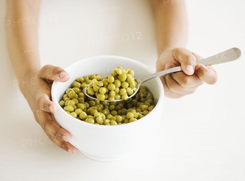 Close up of mixed race girl eating bowl of peas
