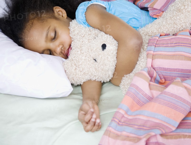 Mixed race girl sleeping with teddy bear