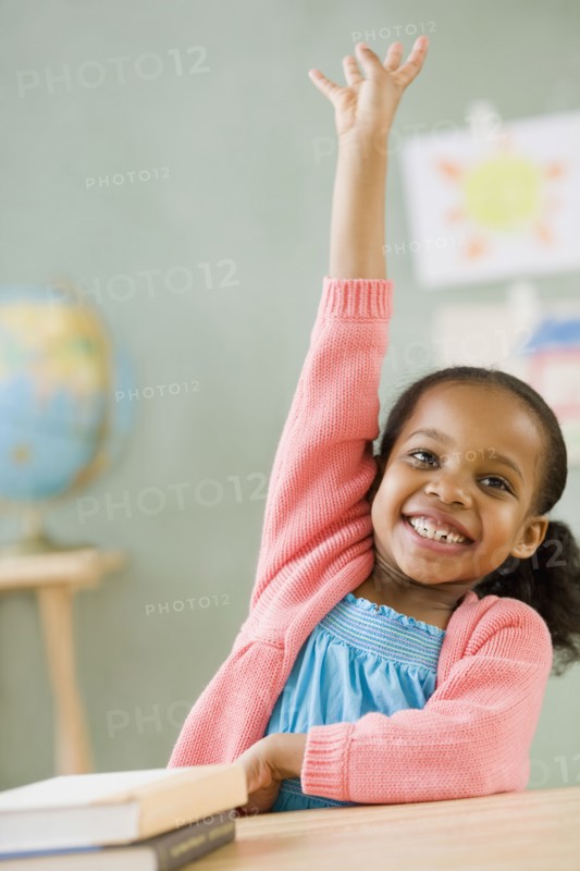 Mixed race girl raising hand to answer question