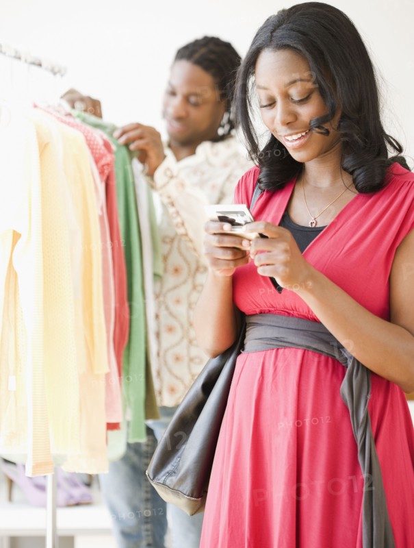 African woman text messaging on cell phone in shop