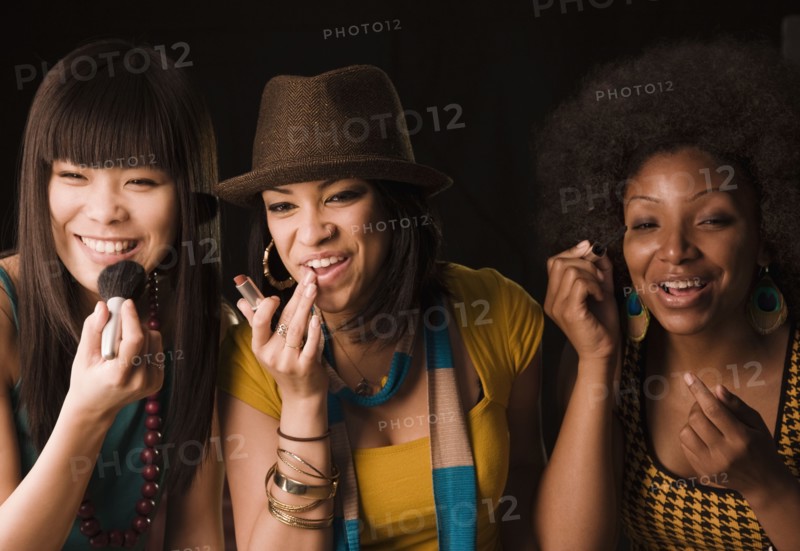 Multi-ethnic women putting on makeup