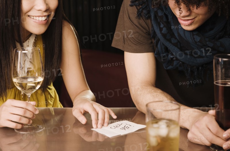 Asian woman giving mixed race man her phone number in nightclub