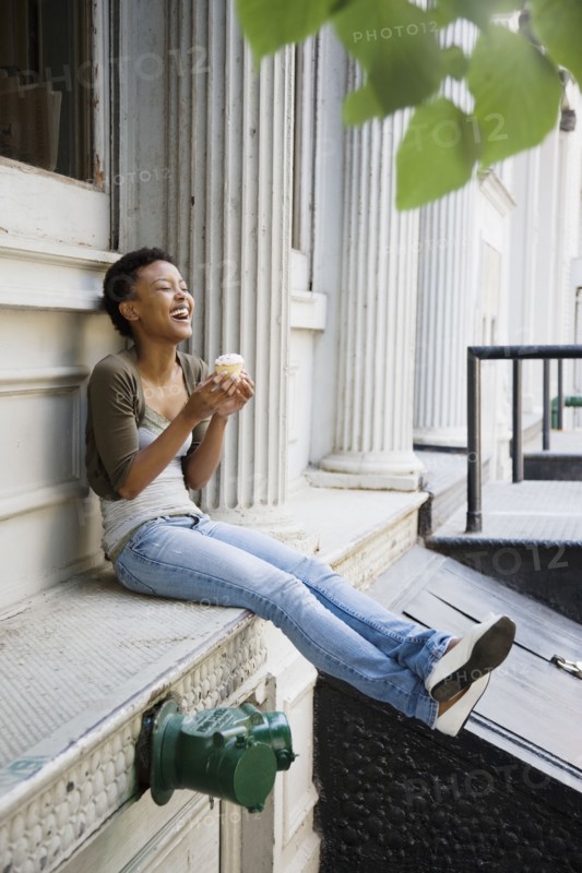 African woman eating cupcake outdoors