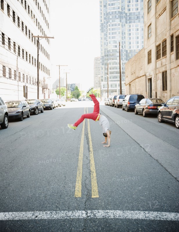 Hispanic teenage boy doing back flip in urban street