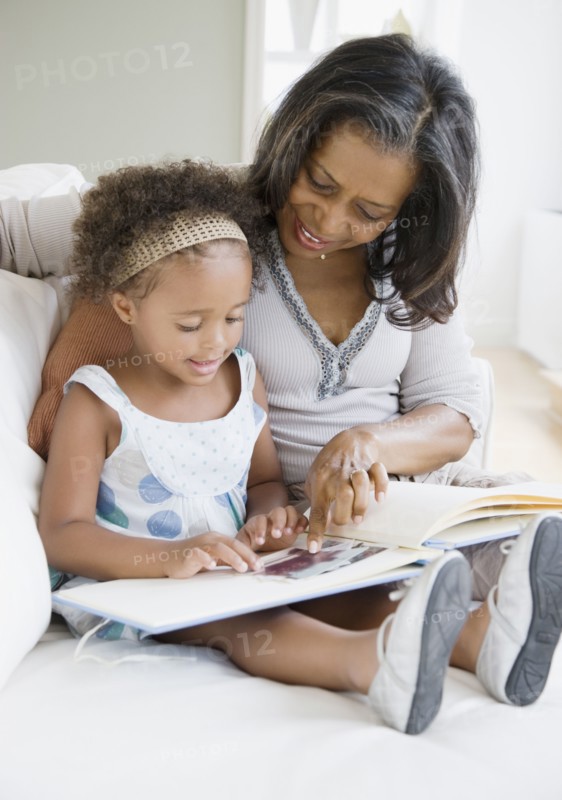 African grandmother looking a photo album with granddaughter