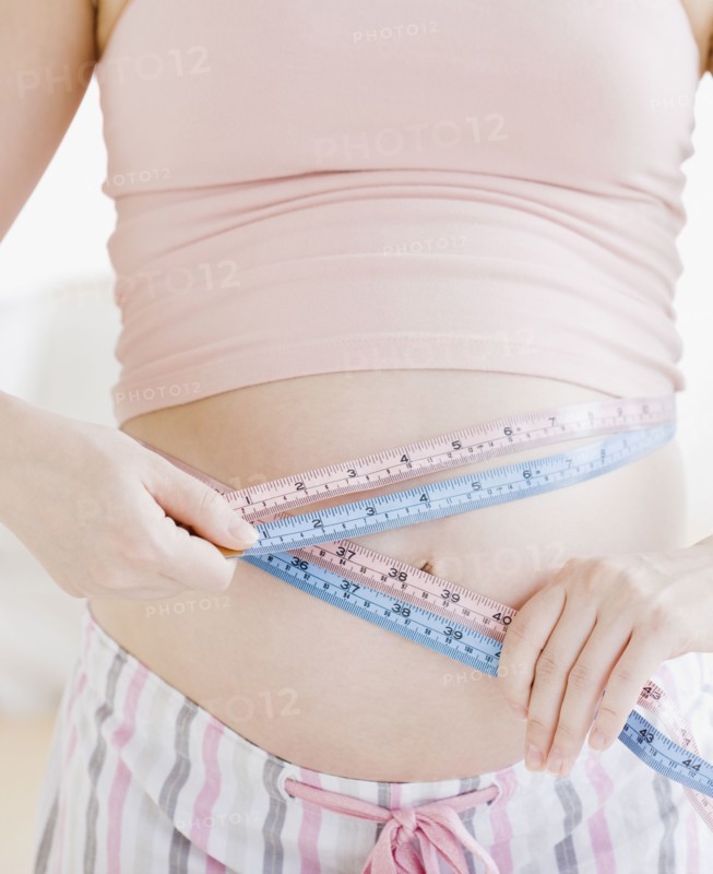 Pregnant Asian woman measuring stomach