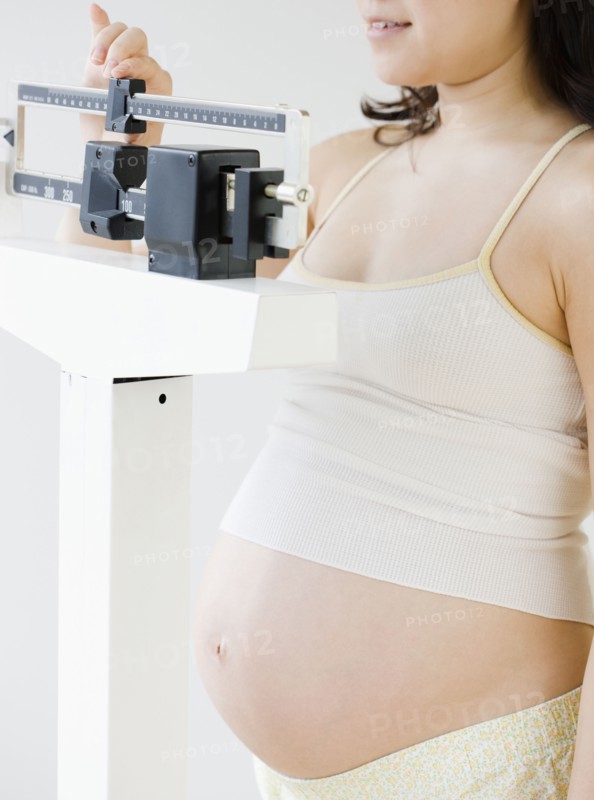 Pregnant Asian woman weighing herself
