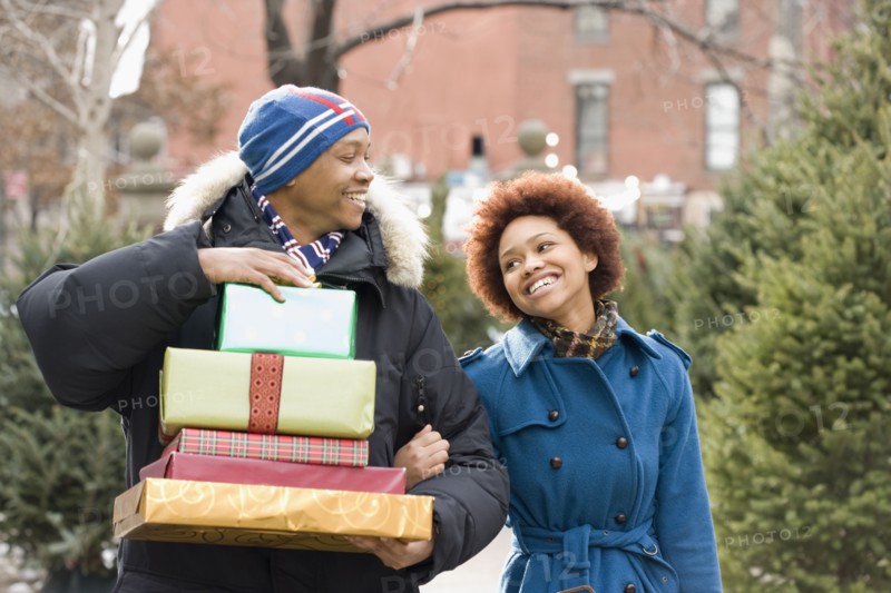 African man carrying stack of Christmas presents for girlfriend