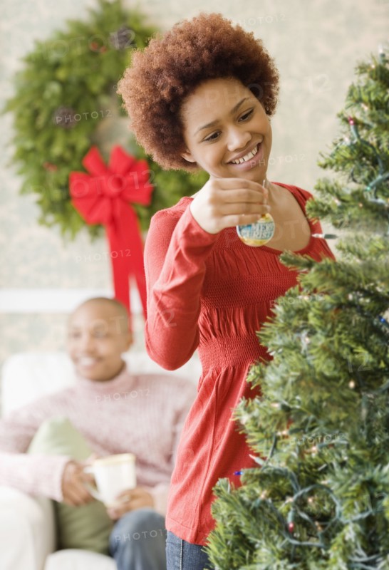 Mixed race woman placing ornament on Christmas tree