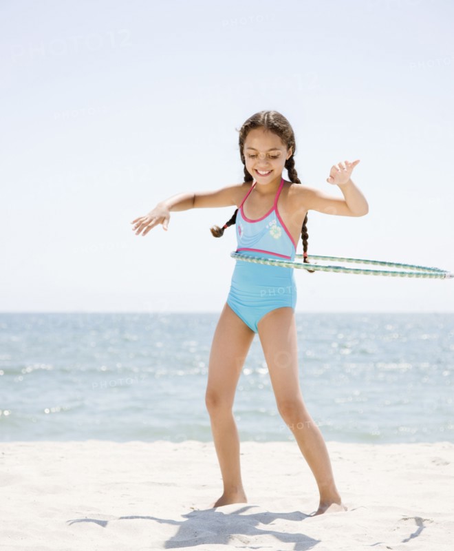 Hispanic girl playing with plastic hoop on beach