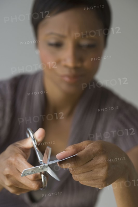 Frustrated African woman cutting up credit card
