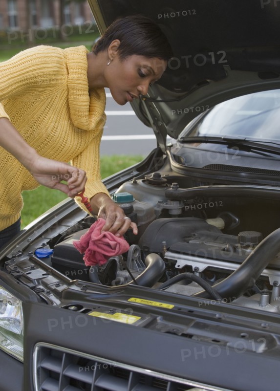 African woman checking oil in car engine