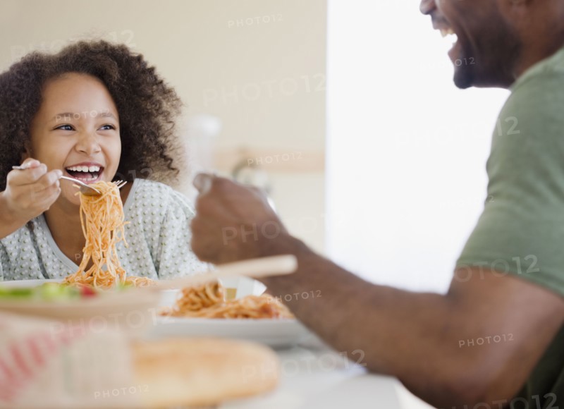 African father and daughter eating pasta