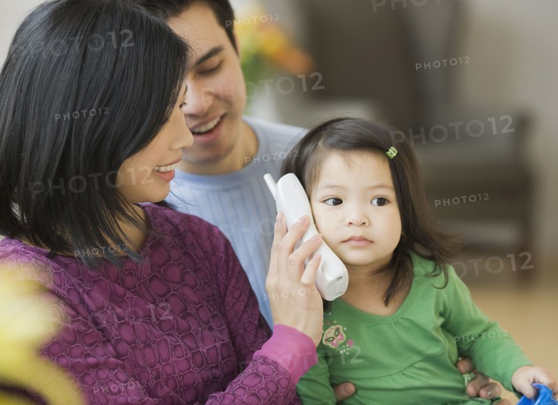 Mother and father holding telephone for daughter