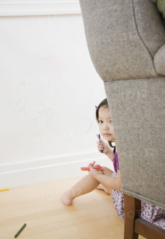 Toddler girl hiding behind chair