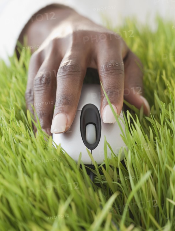 African woman using computer mouse in grass