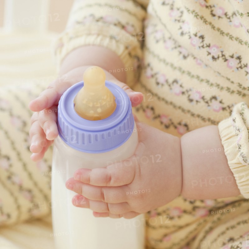 Mixed race baby girl holding bottle