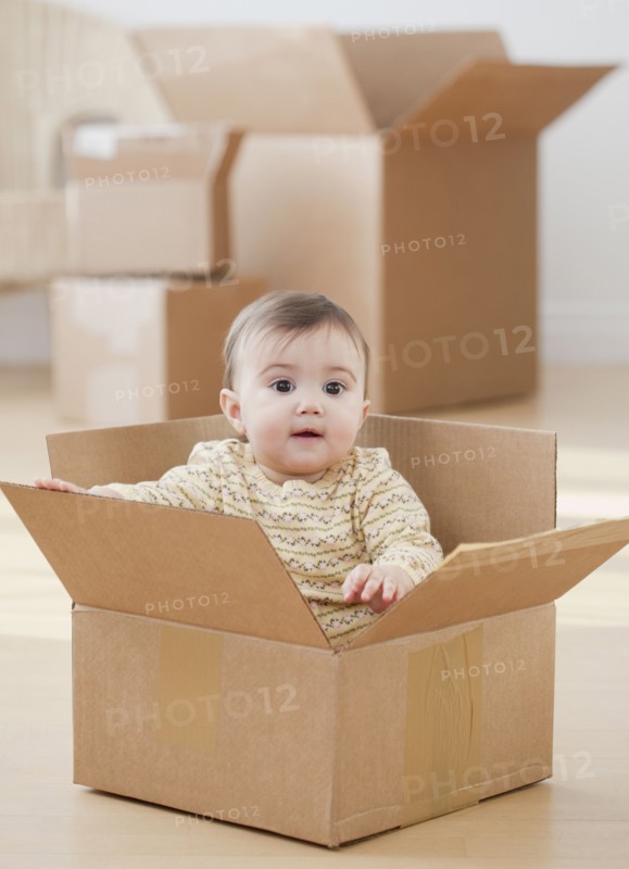 Mixed race baby girl sitting in cardboard box