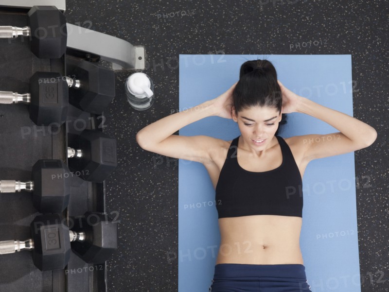 Hispanic woman doing sit-ups in health club