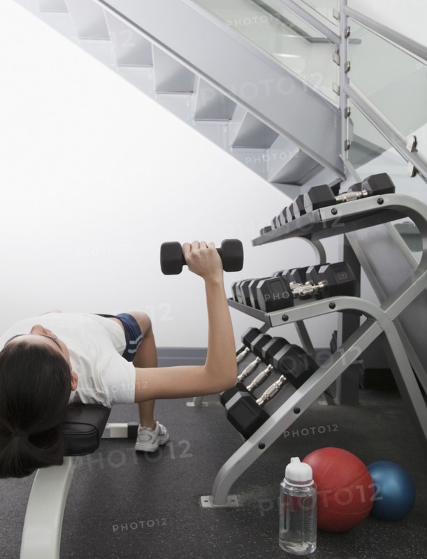 Hispanic woman using hand weights in health club