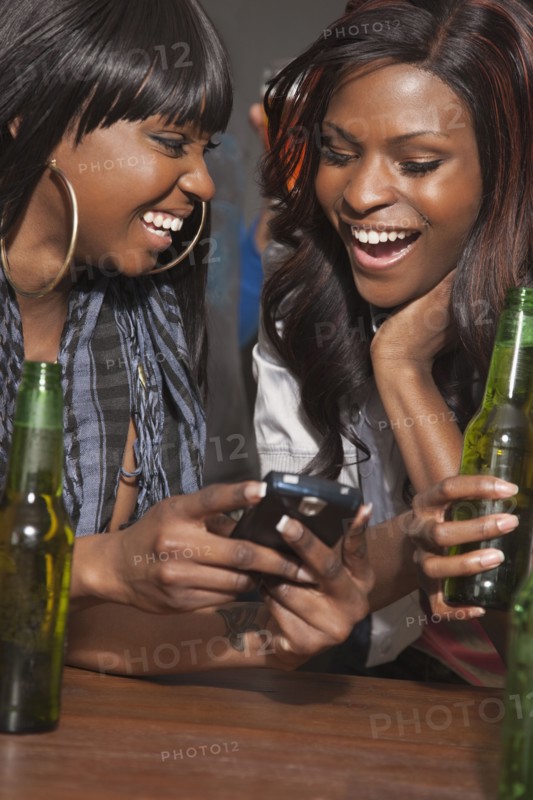 African woman drinking beer and text messaging