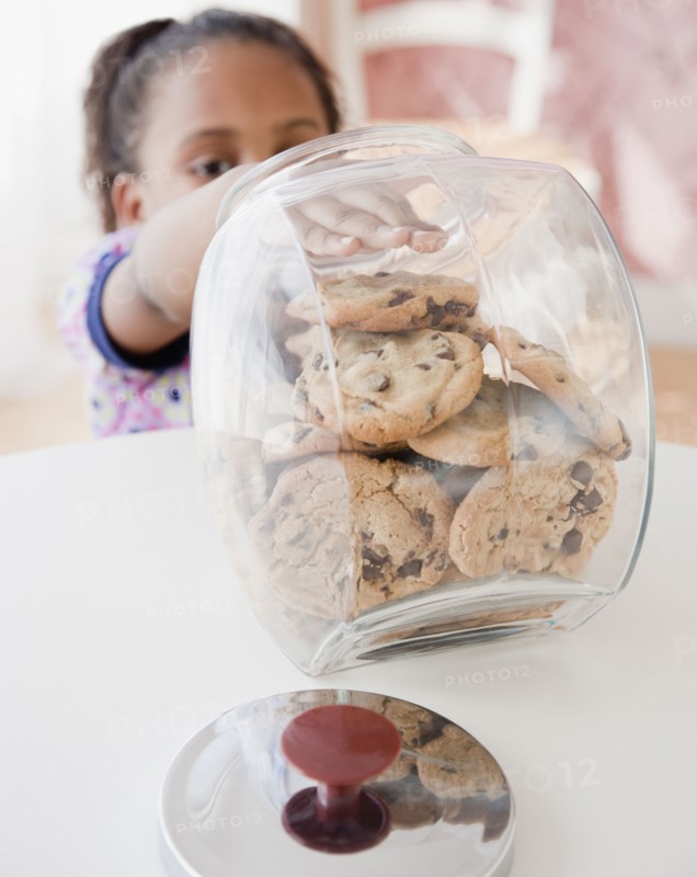 African girl taking cookie from jar