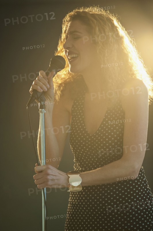 Hispanic woman singing into microphone onstage