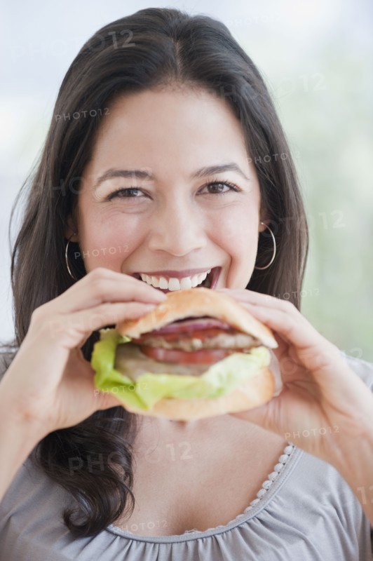 Hispanic woman eating hamburger