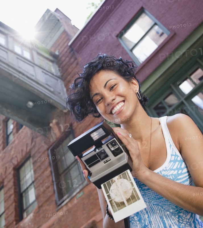 Mixed race woman holding instant camera
