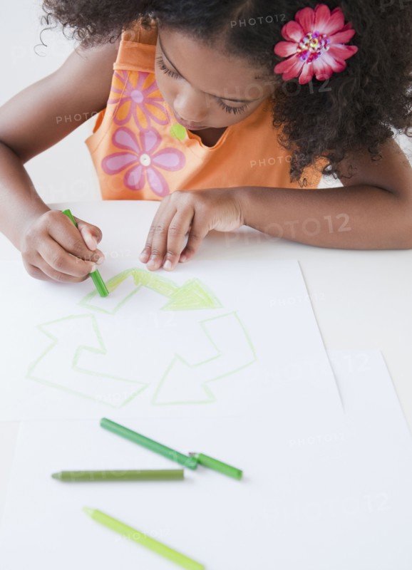 Mixed race girl drawing recycling symbol with crayons