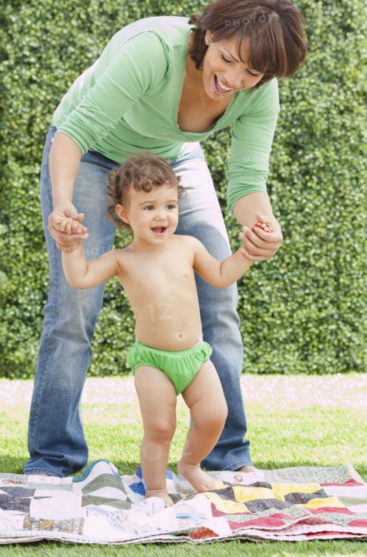 Hispanic mother helping daughter learn to walk
