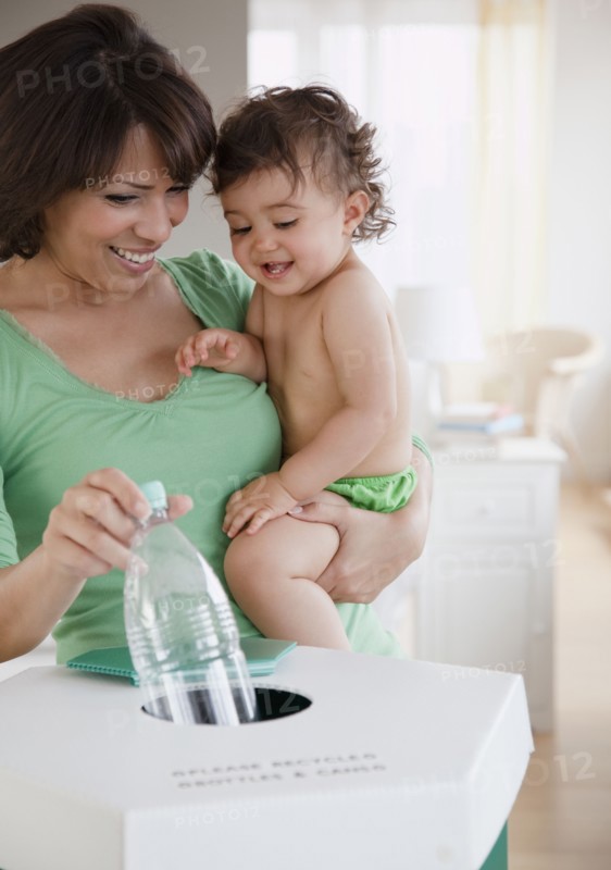 Hispanic mother teaching daughter about recycling